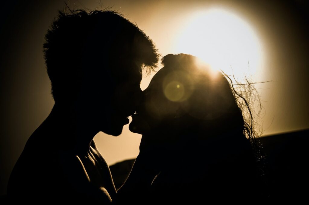Man en vrouw zoenen tijdens zonsondergang